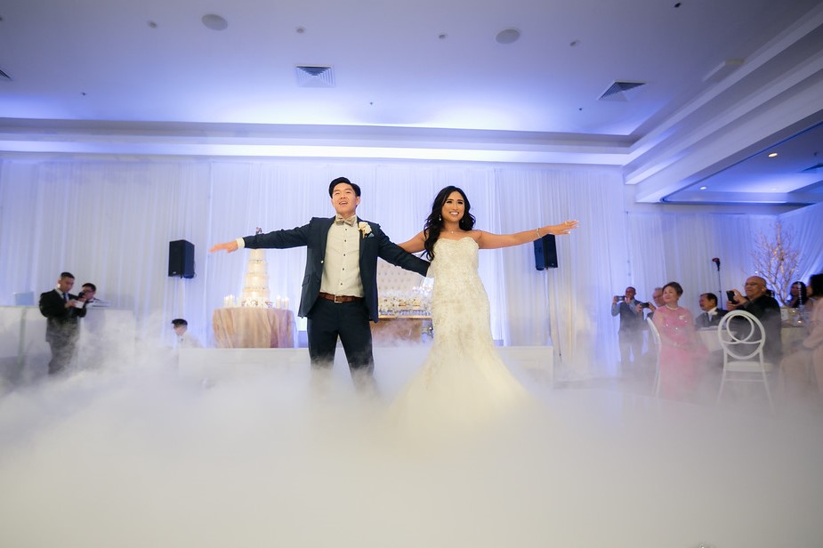 Couple with arms outstretched on a dance floor covered in low cloud