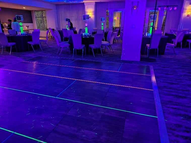 Dark dance floor under blacklight with neon lines glowing along it