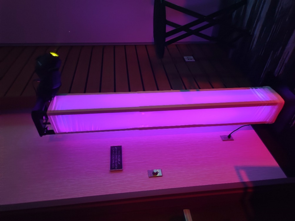 Glow totem lying on its side, its frosted panels glowing magenta