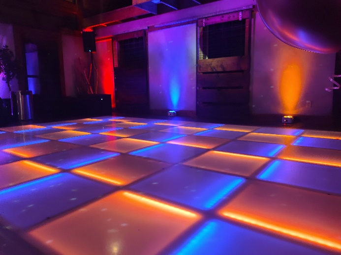 LED dance floor glowing orange and violet in a dark venue lit with colored uplights
