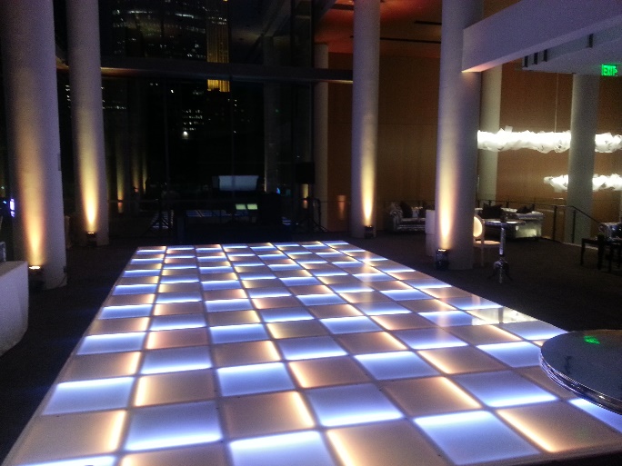 White and amber LED dance floor between uplit columns in a modern event space
