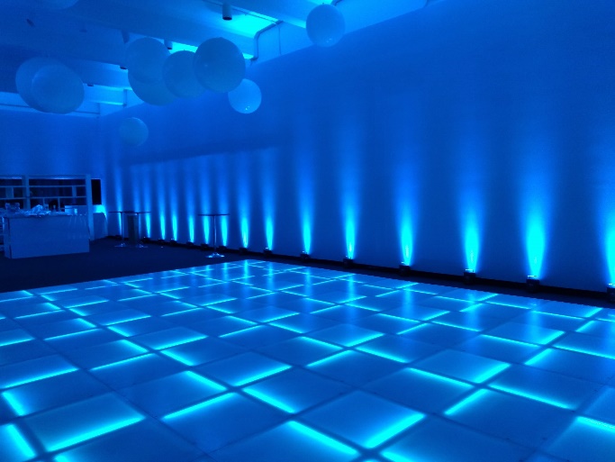 LED dance floor glowing blue in a room washed with blue uplighting, white balloons overhead