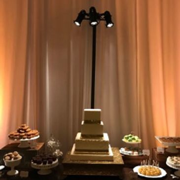 Pin spot lighting a tiered cake on the dessert table
