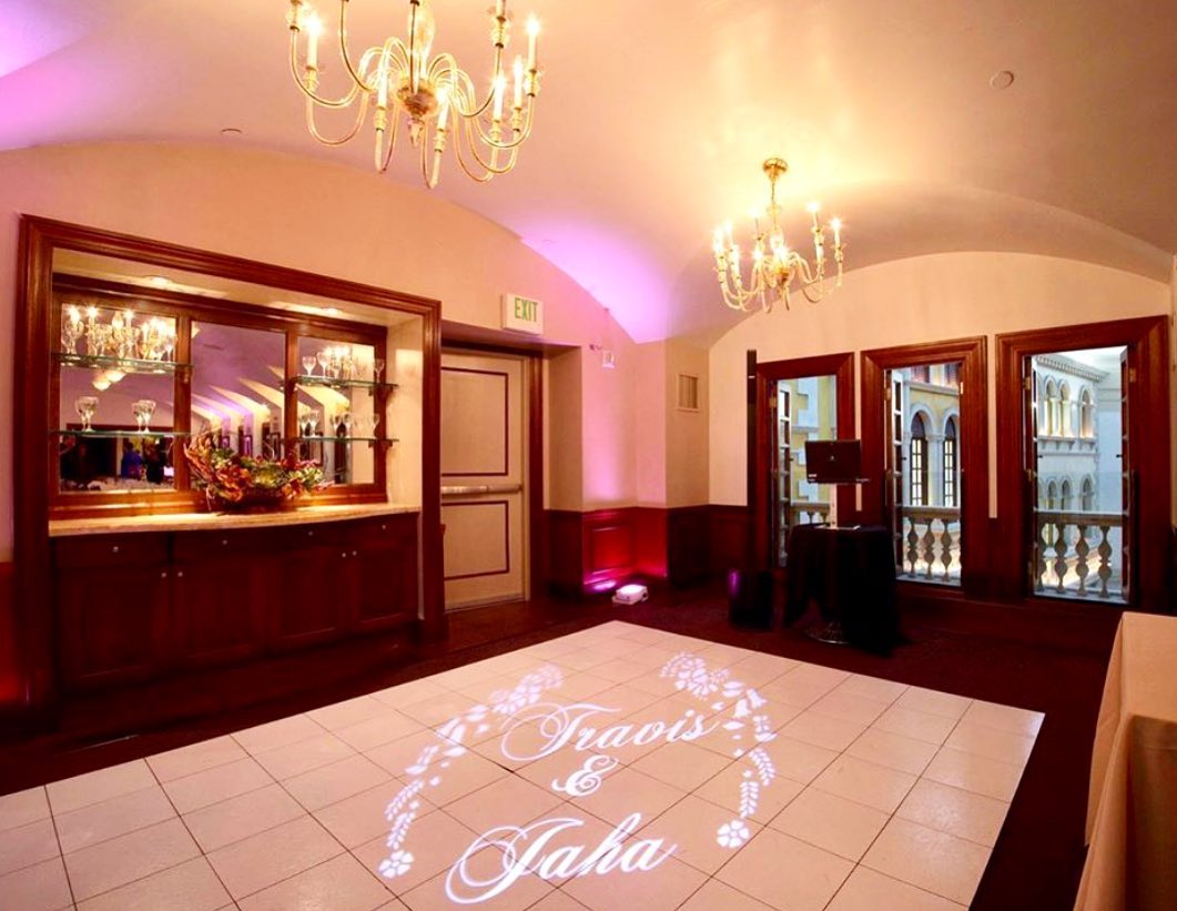 White dance floor with a couple's monogram projected onto it in a chandeliered room