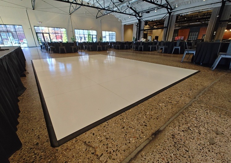 White dance floor with a black edge set up in a large event hall